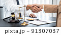 Businesswoman shaking hands with Professional male lawyer after discussing a good deal of contract in the courtroom, Concepts of law, Judge gavel with scales of justice 91307037