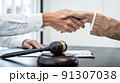 Businesswoman shaking hands with Professional male lawyer after discussing a good deal of contract in the courtroom, Concepts of law, Judge gavel with scales of justice 91307038