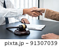 Businesswoman shaking hands with Professional male lawyer after discussing a good deal of contract in the courtroom, Concepts of law, Judge gavel with scales of justice 91307039