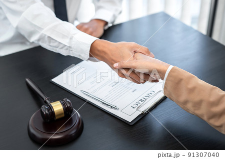 Businesswoman shaking hands with Professional male lawyer after discussing a good deal of contract in the courtroom, Concepts of law, Judge gavel with scales of justice 91307040