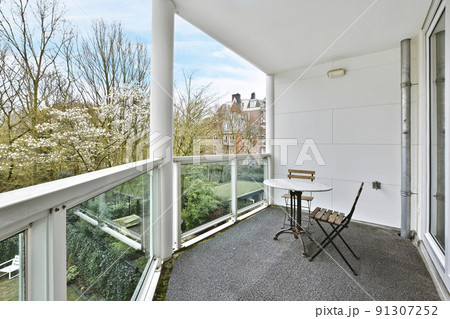 The interior of a delightful balcony with glass handrails and a table 91307252