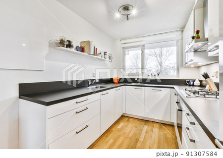 Stylish kitchen with a black countertop and a white kitchen set 91307584