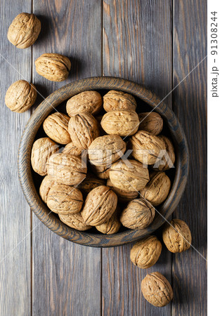 Walnuts in a plate on a brown wooden background. Nuts are a source of vegetable protein. Flat top view Walnuts in a plate on a brown wooden background. Nuts are a source of vegetable protein. Flat top view 91308244