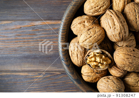 Walnuts in a plate on a brown wooden background. Nuts are a source of vegetable protein. Copy space. Flat top view. 91308247
