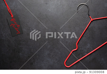 Red coat hangers on a dark concrete background. Black Friday - handwritten inscription on the tag. The concept of holiday sales. Copy space Red coat hangers on a dark concrete background. Black Friday - handwritten inscription on the tag. The concept of holiday sales. Copy space 91309008