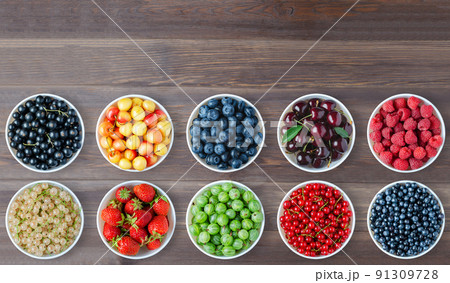 A set of berries in the round plates. Brown wooden background. Copy space. A set of berries in the round plates. Brown wooden background. Copy space. 91309728