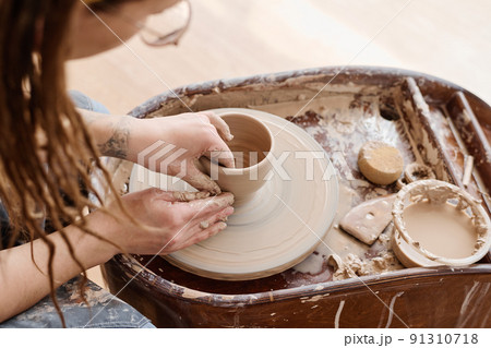 View from above of young creative female pitcher working over new clay item 91310718