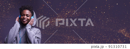 Banner is an African-American woman, wearing headphones. He looks directly into the camera in a sweatshirt against the background of the color of 2022 with sequins. High-quality photography 91310731