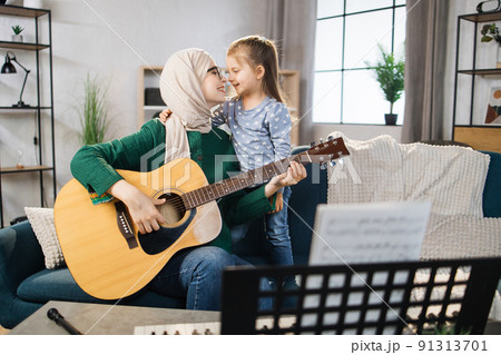 Muslim mom and little happy girl in music therapy by playing guitar on music room. Muslim mom and little happy girl in music therapy by playing guitar on music room. 91313701