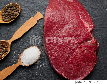 Raw beef tenderloin lies on a wooden cutting board on a black table, top view Raw beef tenderloin lies on a wooden cutting board on a black table, top view 91314858
