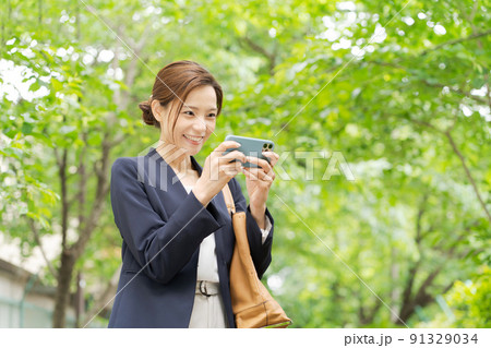 スマホを持つ女性　新緑 91329034
