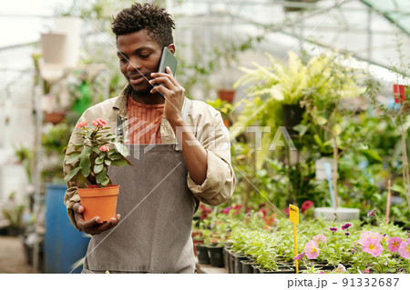 Man with potted flower talking on phone 91332687