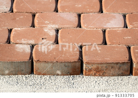 Brown concrete permeable flooring assembled on a substrate of sand. Abstract photo of bricks in the sunlight Brown concrete permeable flooring assembled on a substrate of sand. Abstract photo of bricks in the sunlight 91333705
