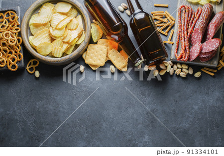 Beer in glass bottles, salty snacks for beer and sausages. Food and drinks for the party. Photo for a pub or restaurant menu. Free space for text 91334101