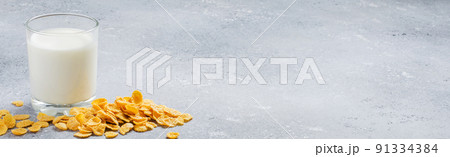 Corn flakes on a concrete background and milk in a glass. Side view. Copy space Corn flakes on a concrete background and milk in a glass. Side view. Copy space 91334384