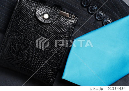 Blue men's necktie, jacket sleeve, and black wallet. Concept image of a successful business man 91334484