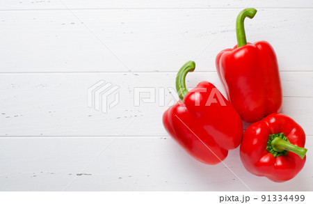 Three red ripe bell peppers. White wooden background. The view from the top. Copy space Three red ripe bell peppers. White wooden background. The view from the top. Copy space 91334499