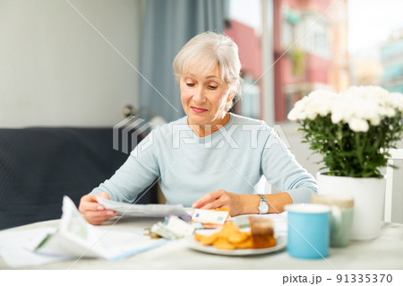 Elderly woman counting money at home 91335370
