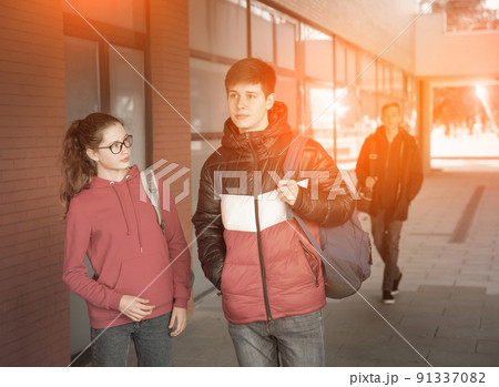 Portrait of two students carrying bags walking and talking Portrait of two students carrying bags walking and talking 91337082