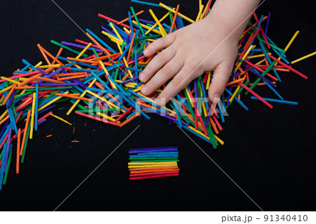 Kid playing with coloured wooden  sticks for creativity 91340410