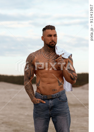 Handsome young muscular italian man posing shirtless on the beach, sunset summer time 91341907
