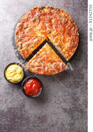 Savory Southern Style Cheeseburger Pie with ground beef cheddar cheese and onion close-up on a slate board. vertical top view 91342550
