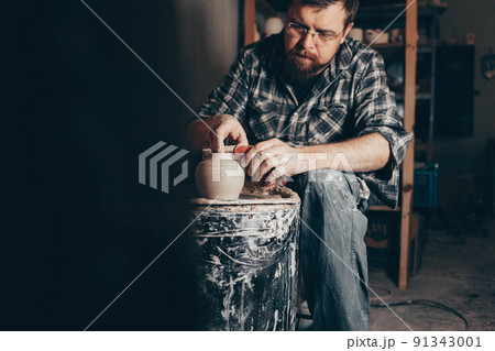 Man works on the potter's wheel creating a jug of clay. Man works on the potter's wheel creating a jug of clay. 91343001