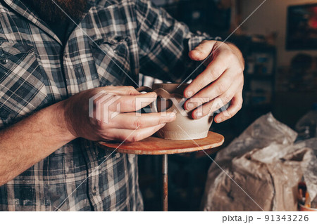 Potter decorates the ceramic cup. 91343226