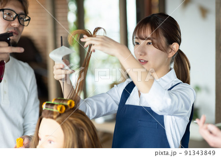 パーマの練習をする若いスタッフと講師 パーマの練習をする若いスタッフと講師 91343849