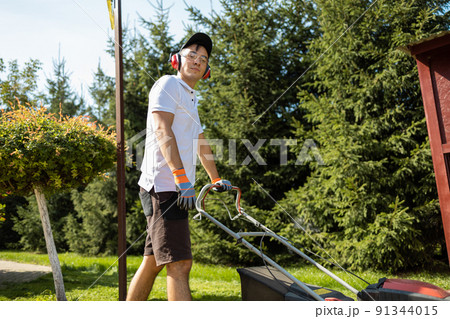 Gardener mowing the grass with a gasoline lawn mower Gardener mowing the grass with a gasoline lawn mower 91344015