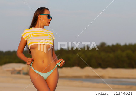 Sexy model in crop top and bikini panties on beach Sexy model in crop top and bikini panties on beach 91344021