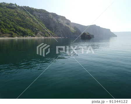 Aerial view from above on calm azure sea and volcanic rocky shores. Small waves on water surface in motion blur. Nature summer ocean sea beach background. Nobody. Holiday, vacation and travel concept 91344122