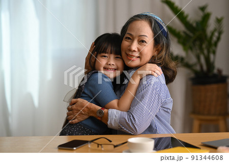 Affectionate grandmother cuddling her sweet lovely granddaughter and smiling at camera. Loving family relationship concept Affectionate grandmother cuddling her sweet lovely granddaughter and smiling at camera. Loving family relationship concept 91344608