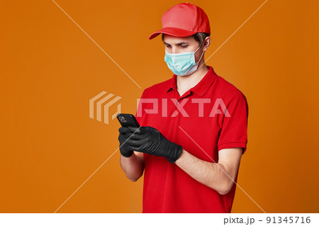 Delivery man employee in red cap face mask, empty cardboard box 91345716