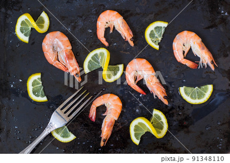 shrimp, lemon and sea salt with fork on a dark black background shrimp, lemon and sea salt with fork on a dark black background 91348110