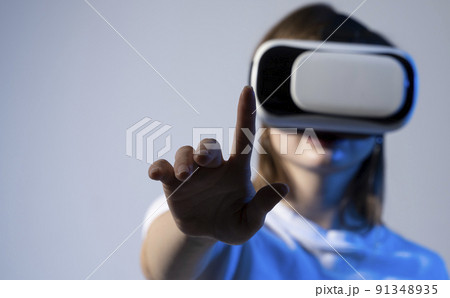 Woman in VR headset trying to touch objects in virtual reality. Woman in VR headset trying to touch objects in virtual reality. 91348935