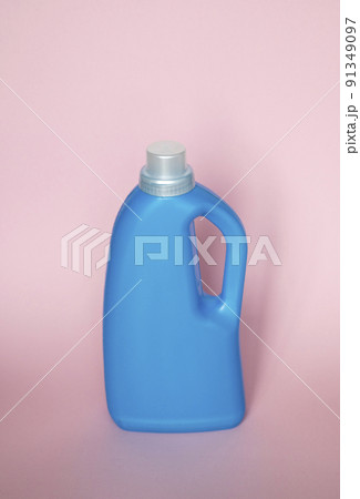 Blue plastic bottle stands on pink background. Conditioner or liquid powder for washing. Capacity with space for copying. Layout for logo application. 91349097