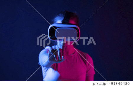 Metaverse technology concept. Woman with VR virtual reality goggles trying to touch something with a finger. Futuristic lifestyle. Metaverse technology concept. Woman with VR virtual reality goggles trying to touch something with a finger. Futuristic lifestyle. 91349480