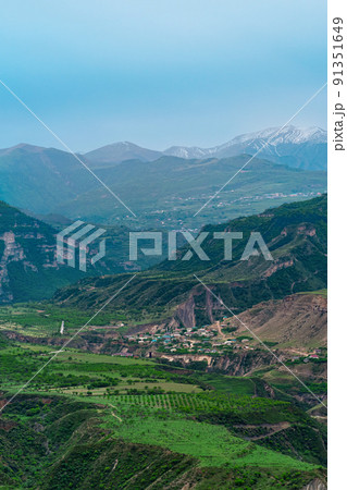 foggy alpine valley with villages and fields between mountain peaks in Dagestan 91351649