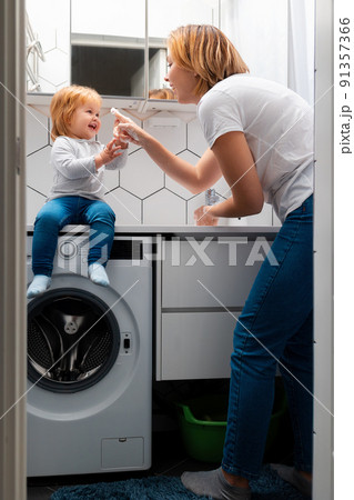 Smiling little girl learns to wash her hands together with her mother. Bedtime hygiene procedures. Vertical Smiling little girl learns to wash her hands together with her mother. Bedtime hygiene procedures. Vertical 91357366