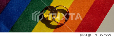 Legalization of same-sex marriages. Rainbow flag and wedding rings. 91357559