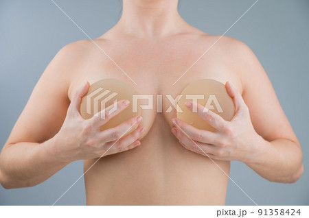 Caucasian naked woman trying on silicone breast implants. Caucasian naked woman trying on silicone breast implants. 91358424