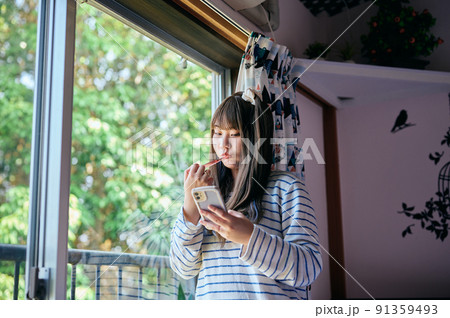 窓際で歯磨きをする若い女性 91359493