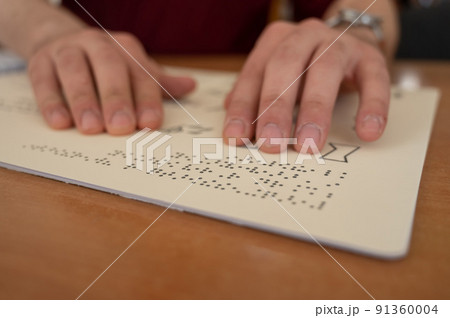 Visually impaired man reading a braille book. Visually impaired man reading a braille book. 91360004