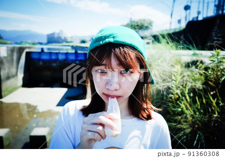 河川敷でアイスを食べる女の子 91360308