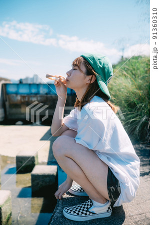 河川敷でアイスを食べる女の子 91360310