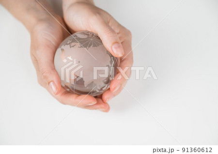 Crystal globe in female hands on a white background. Crystal globe in female hands on a white background. 91360612