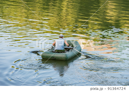 Man floats by inflatable boat on the river. 91364724