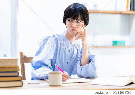 リビングで勉強中に不満顔の眼鏡をかけた若い女性 リビングで勉強中に不満顔の眼鏡をかけた若い女性 91366750