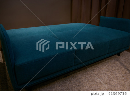 Minimalist comfortable and orthopedic dark blue and green sofa bed in a folding form, on display in a furniture store. Home interior design concept 91369756
